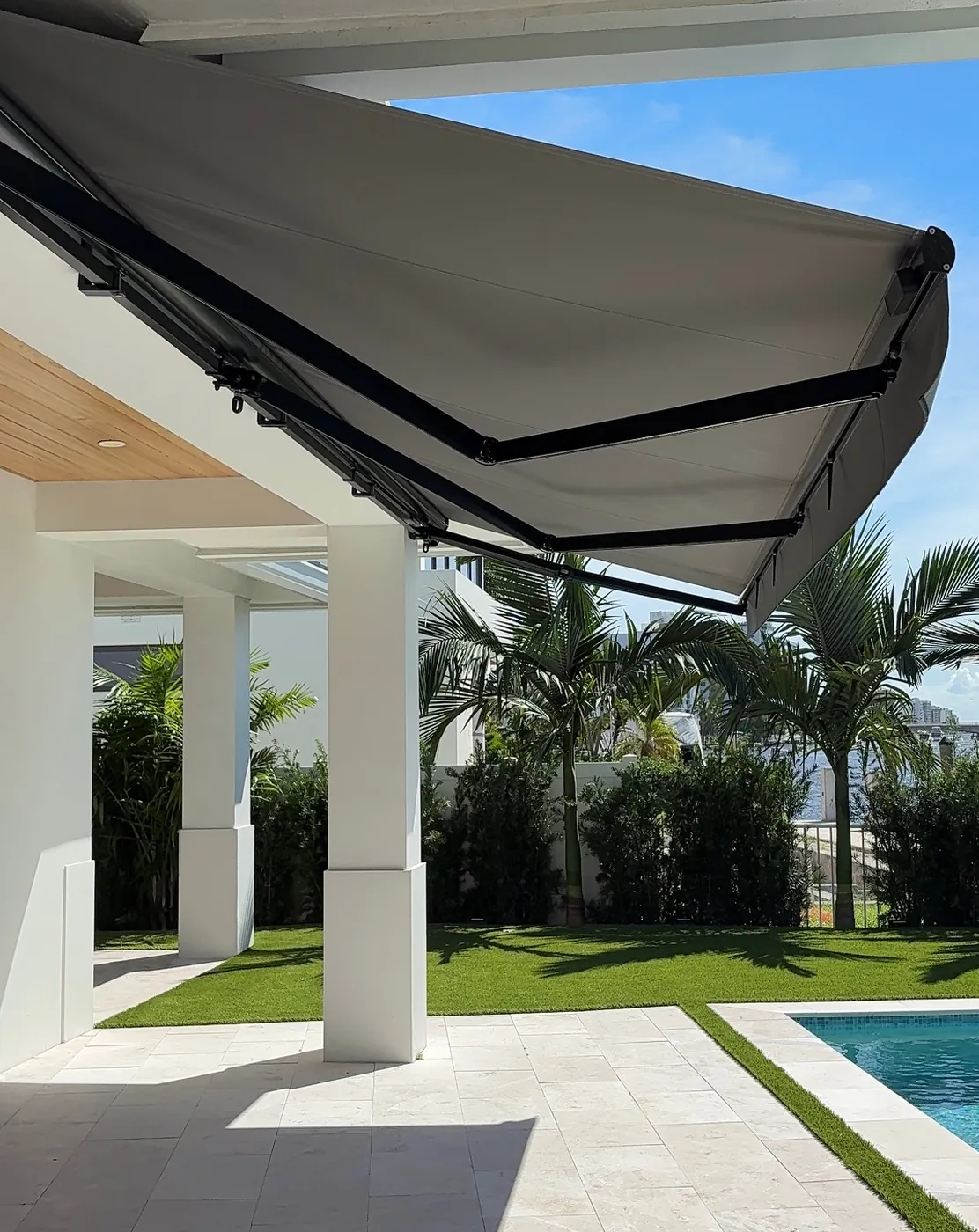 Modern Motorized Awning Extended Over Poolside Patio in Sunny Garden